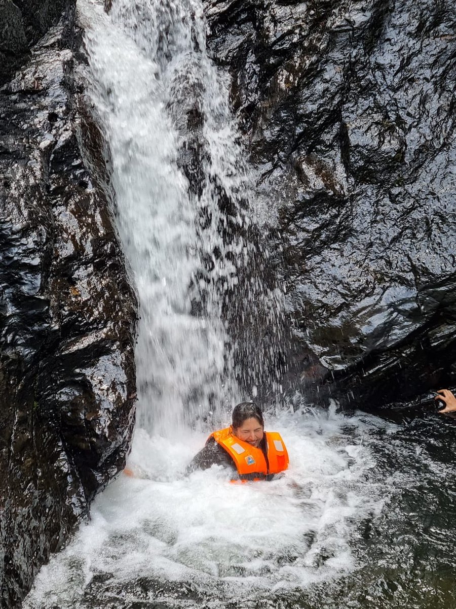 Ayesha laughing in a life jacket beneath a rushing waterfall